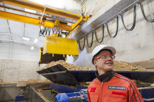 A person standing in front of a crane wearing safety gear.