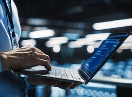 Close-up of a laptop comptures a man is working with.