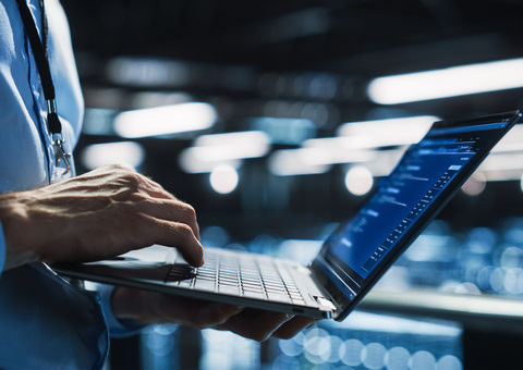 Close-up of a laptop comptures a man is working with.