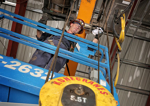 The technician repairs the overhead crane.